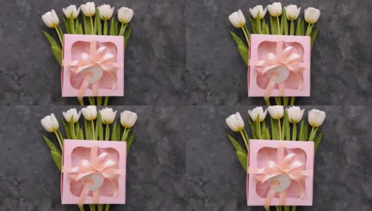 白色郁金香花与粉色礼盒和心卡标签在黑暗的背景平lay。4K视频8三月妇女节快乐的概念。春天鲜花花束高清在线视频素材下载