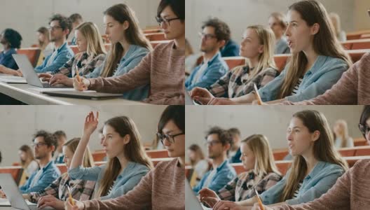 年轻漂亮的学生在大学听讲座时使用笔记本电脑，她举手向讲师提问。现代聪明学生的多民族群体。高清在线视频素材下载