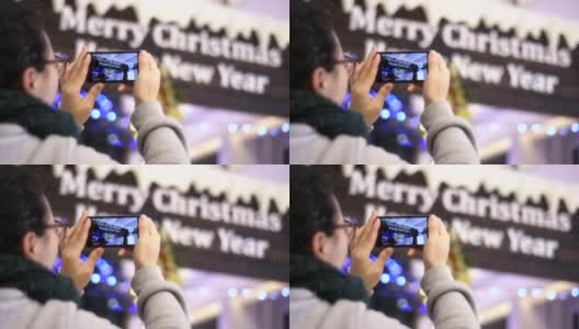 一个中国女孩在圣诞树下用手机拍照高清在线视频素材下载