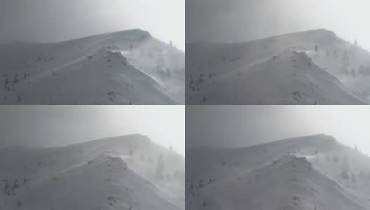 在冬季的暴风雪中，高速风从山脊上吹起雪花高清在线视频素材下载