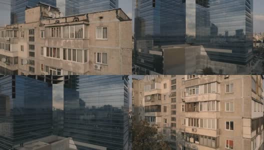 玻璃幕墙的摩天大楼靠近旧的多套公寓大楼。镜头从旧房子移到新楼。鸟瞰图高清在线视频素材下载