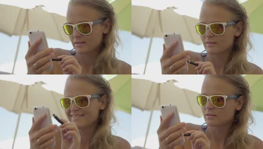 戴墨镜的女人在海滩上用手机高清在线视频素材下载