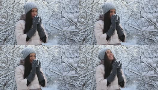美丽快乐的女孩用热茶暖身。冰雪覆盖的树木在冬季公园高清在线视频素材下载
