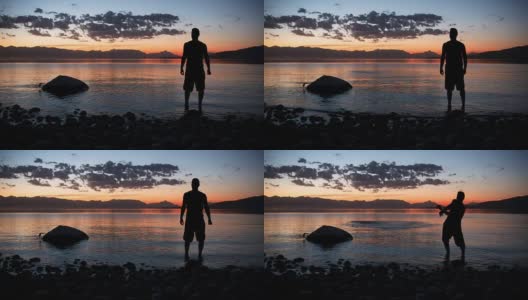 一个人的剪影扔石头的湖和美丽的日落在山上高清在线视频素材下载