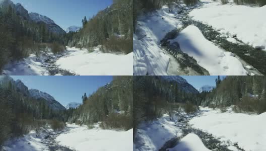 倾斜向上的镜头，一个流动的溪流通过雪谷景观包围在森林在冬天在圣胡安山脉(落基山脉)外奥雷，科罗拉多州在一个阳光明媚的日子高清在线视频素材下载