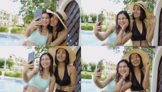 两名身穿比基尼泳装的亚洲女性在游泳池前自拍和拍照。积极情绪与慢动作。高清在线视频素材下载
