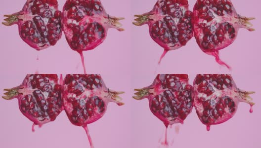 果汁流下来的一半天然红石榴水果在粉红色的工作室背景，健康的饮食理念高清在线视频素材下载