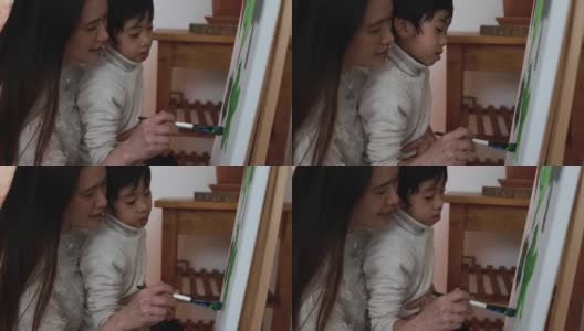 亚洲母亲有乐趣做颜色油漆与小儿子在画布上在家-母亲和孩子的爱高清在线视频素材下载