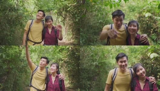 年轻的亚洲男人和女人朋友一起在森林里旅行。情侣们在大自然中感受清新和放松，一边看一边指着风景，然后一边拥抱和幸福地走着高清在线视频素材下载