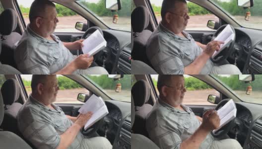 一个白人老人坐在驾驶座上看书高清在线视频素材下载