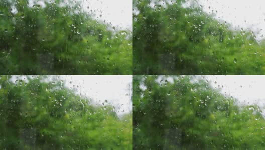 雨滴落在窗户上的4K原始视频，在绿树摇曳的散景背景下特写。高清在线视频素材下载