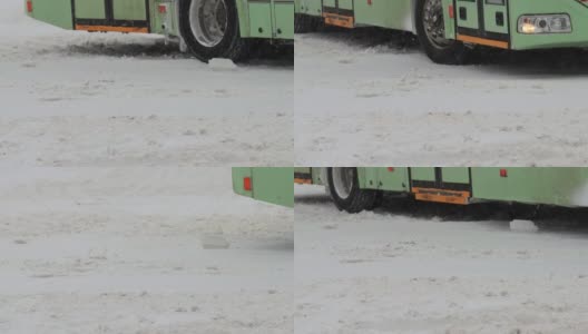 冬天。公共城市交通巴士正行驶在城市的雪道上。用慢动作对车轮轮胎进行特写。降雪。交通状况不佳，暴风雪。有发生交通事故的危险。十字路口高清在线视频素材下载
