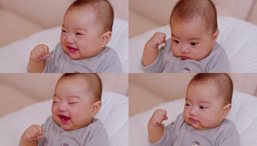 可爱的亚洲女婴躺在床上看着相机。可爱的小婴儿微笑着，幸福放松在床上。亚洲婴儿在卧室新生肖像，软焦点高清在线视频素材下载
