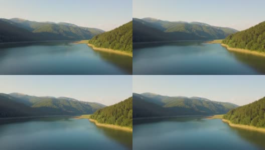 鸟瞰大湖，清澈湛蓝的水之间的高山覆盖着茂密的常绿森林。高清在线视频素材下载