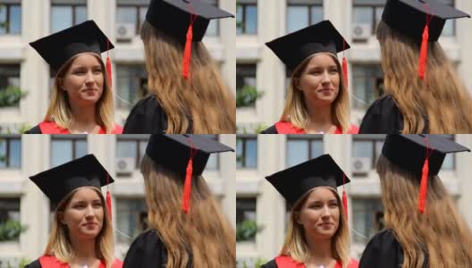 戴着学位帽的金发女人在听最好的朋友的毕业典礼高清在线视频素材下载