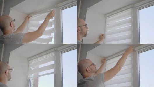 一个大胆的勤杂工在室内窗户上安装百叶窗的特写镜头高清在线视频素材下载