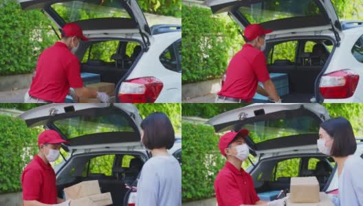 亚洲快递员戴着口罩穿着红色制服，搬运包裹盒子给女顾客走到房前。新冠肺炎期间的邮差及快递杂货送货服务。高清在线视频素材下载