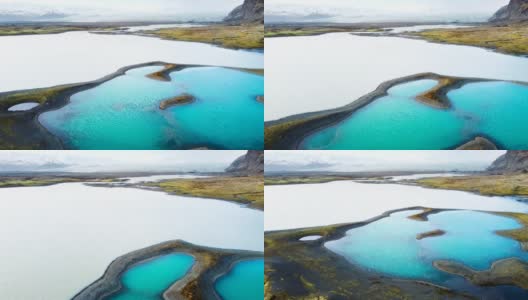 神奇的空中飞行在冰岛上空，从鸟瞰，这里是一片有着绿色苔藓和蓝绿色湖泊的火山景观。美丽而原始的自然高清在线视频素材下载