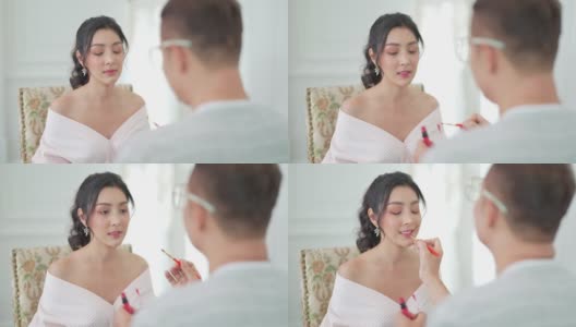 4K亚洲男化妆师为身着白色婚纱的新娘化妆。高清在线视频素材下载