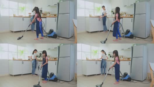 亚洲漂亮的母亲教小女孩打扫厨房在家里。爱美丽的父母妈妈帮助和支持小女儿在家打扫房间的地板。活动关系的概念。高清在线视频素材下载