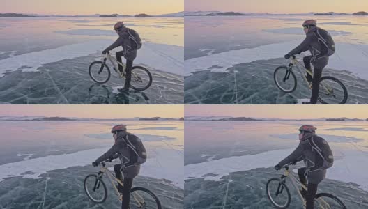 男人把自行车放在冰上。他看着美丽的日落。骑自行车的人穿着灰色羽绒服，背着背包，戴着头盔。结冰的贝加尔湖的冰。旅行者正在骑自行车。高清在线视频素材下载