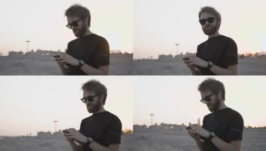在海滩上用智能手机发短信的男人高清在线视频素材下载