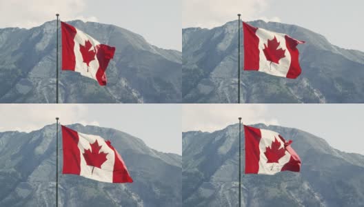加拿大国旗在风中吹动的慢动作镜头与山在一个阳光明媚的日子的背景高清在线视频素材下载