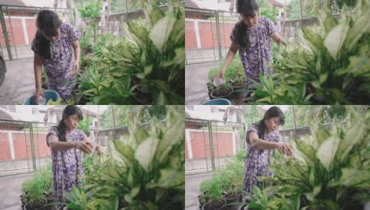 亚洲退休老年妇女在她家门前用回收塑料杯作为喷壶给菜园浇水，积极的老年生活方式的概念，侧视图高清在线视频素材下载