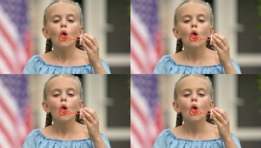 可爱的小女孩在镜头前吹肥皂泡微笑，童年快乐高清在线视频素材下载