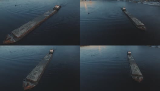 日落航拍画面显示，驳船在城市港口附近的河上航行高清在线视频素材下载