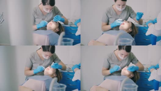 计划牙科检查。在医生治疗病人时，一个女人张着嘴坐在牙医的椅子上高清在线视频素材下载