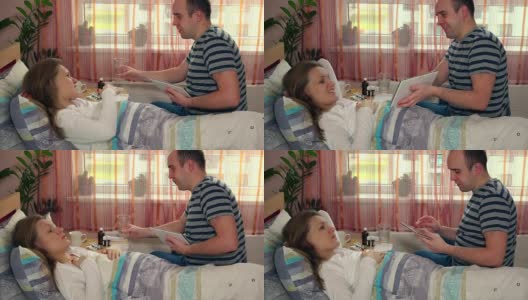 男人丈夫用平板电脑娱乐他生病的妻子在床上的女人高清在线视频素材下载