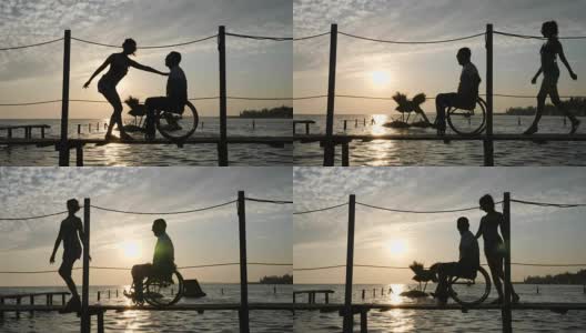 残疾人士过着充实的生活年轻妇女和男性残疾在轮椅上码头在背景天堂在橙色的阳光高清在线视频素材下载