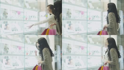 两个女孩在购物中心看珠宝店的橱窗。高清在线视频素材下载