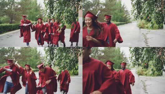 慢镜头中，快乐的毕业生们穿着红袍和红帽，挥舞着毕业证书，微笑着在校园里奔跑。美丽的树木和灌木可见，下雨了。高清在线视频素材下载