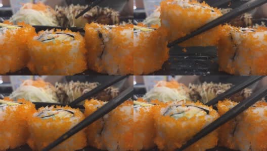 年轻的亚洲女人用筷子吃寿司，加州卷，日本食物高清在线视频素材下载