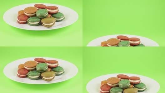 绿色屏幕上的盘子里装着美味的彩色杏仁饼干高清在线视频素材下载