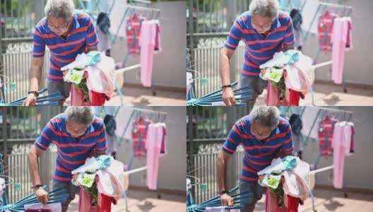 亚洲华人老人收集挂在前院清洗后的衣服高清在线视频素材下载