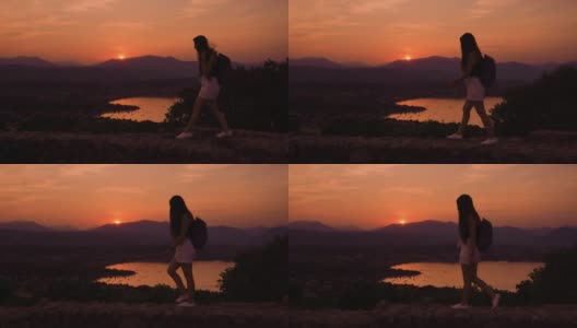 女孩在山中美丽的日落上散步高清在线视频素材下载