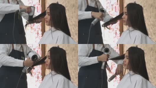 在现代美容院，美发师用吹风机给美女做头发。高清在线视频素材下载