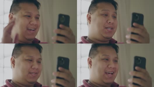 一名亚洲男子微笑着用手机进行视频通话高清在线视频素材下载