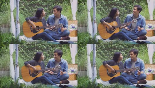年轻的亚洲情侣在公园里，户外弹吉他高清在线视频素材下载