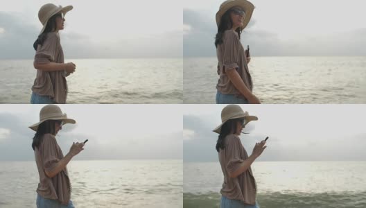在海滩上用手机看日落的女人高清在线视频素材下载