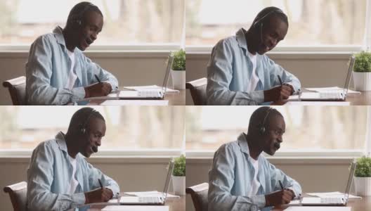 一个戴着耳机的非洲人用笔记本电脑在网上学习外语高清在线视频素材下载