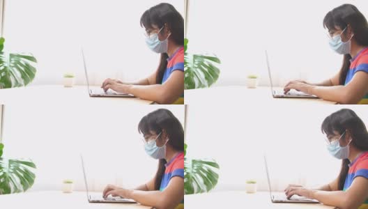 带口罩的亚洲商务女性在家庭办公室使用电脑，由于病毒危机在家里工作的商务人士高清在线视频素材下载