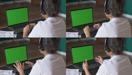 一个年轻的印度女人用一台绿屏笔记本电脑与客户交流的特写，在线电话会议，与人培训，使用电脑。众议院椅子上明亮的房间高清在线视频素材下载