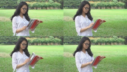 女学生在大学公园看书高清在线视频素材下载