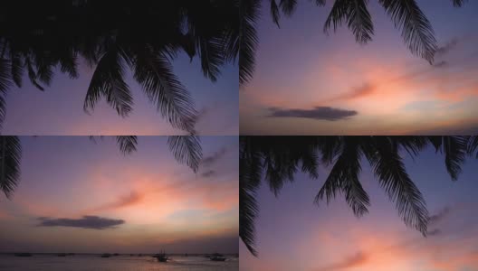 海滩上美丽的日落，有棕榈树和小船。高清在线视频素材下载