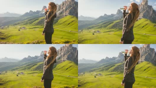 一名女子站在山顶俯瞰山谷，用可重复使用的水瓶喝水高清在线视频素材下载