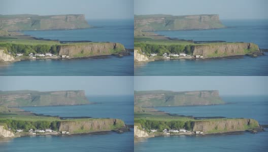 令人惊叹的风景郁郁葱葱的悬崖和美丽的房子在安特里姆海岸，爱尔兰被平静的蓝色海洋包围-宽镜头高清在线视频素材下载